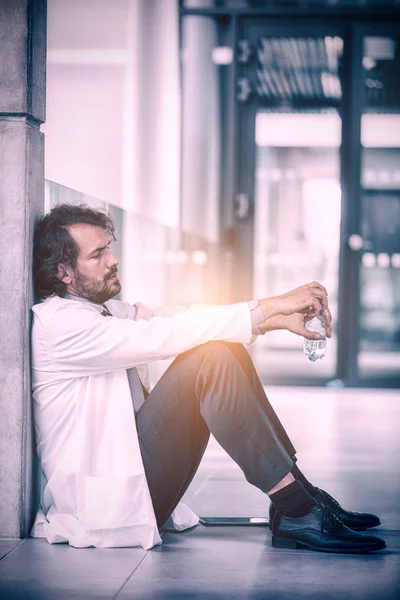 Doctor sitting on floor at hospital — Stock Photo, Image