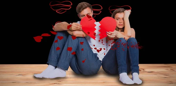 Jovem casal segurando coração quebrado — Fotografia de Stock