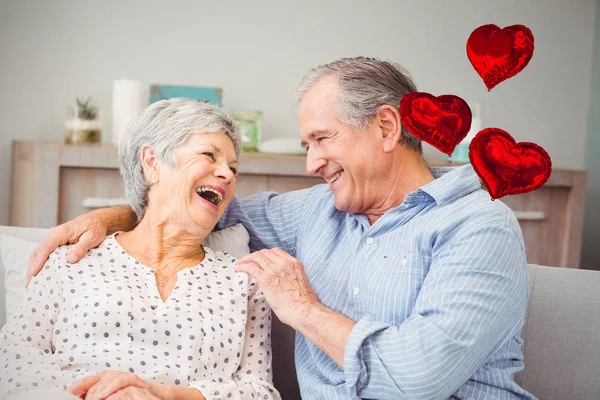 Pareja riendo mientras se sienta en el sofá — Foto de Stock