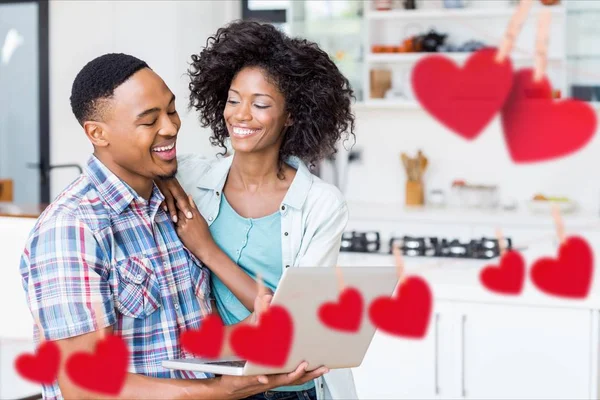 Casal sorrindo usando laptop na cozinha — Fotografia de Stock