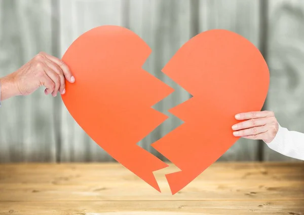 Manos de pareja sosteniendo un corazón roto — Foto de Stock