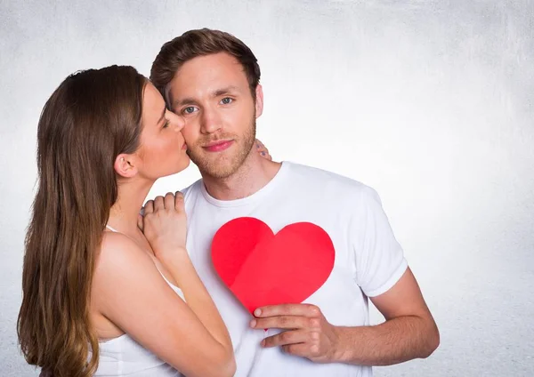 Mujer besar hombre mientras celebración de corazón —  Fotos de Stock