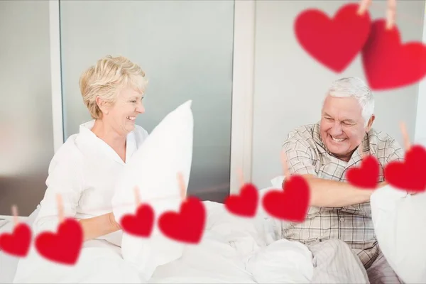 Casal sênior tendo travesseiro luta no quarto — Fotografia de Stock