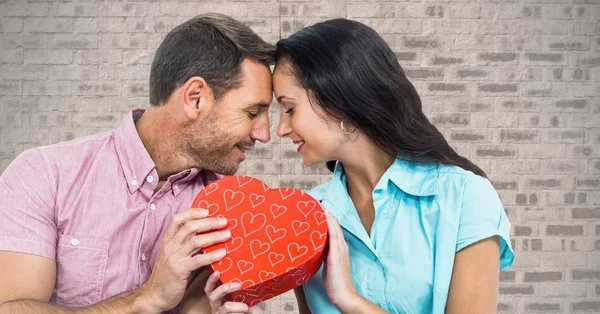 Romántica pareja sosteniendo la forma del corazón caja de regalo —  Fotos de Stock