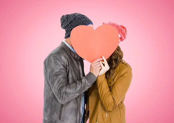 Couple hiding face behind orange heart — Stock Photo, Image