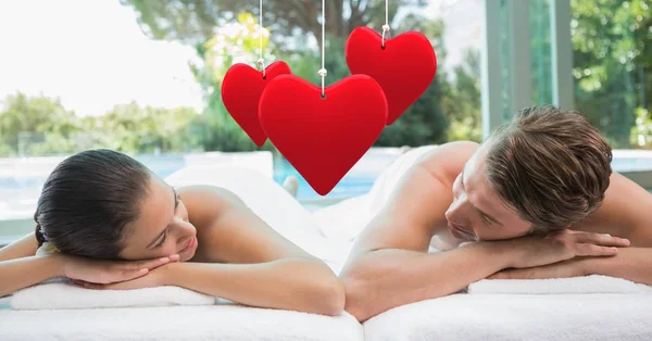Hängendes rotes Herz und Paar liegen im Wellnessbereich — Stockfoto