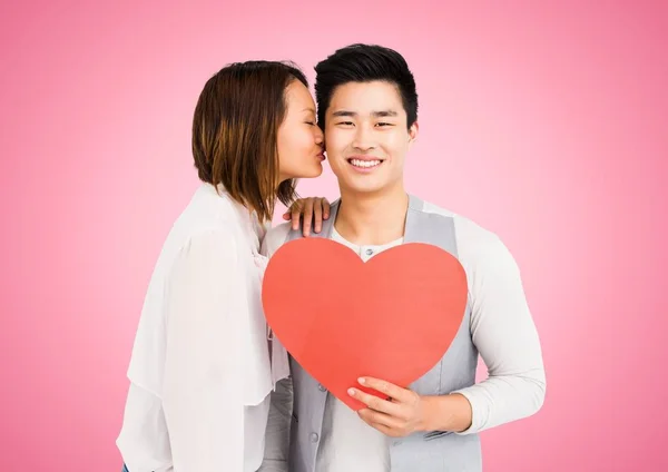 Woman kissing man while holding heart — Stock Photo, Image