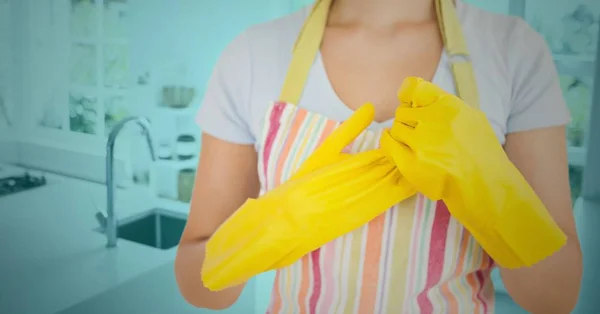 Mulher removendo luvas de borracha na cozinha — Fotografia de Stock