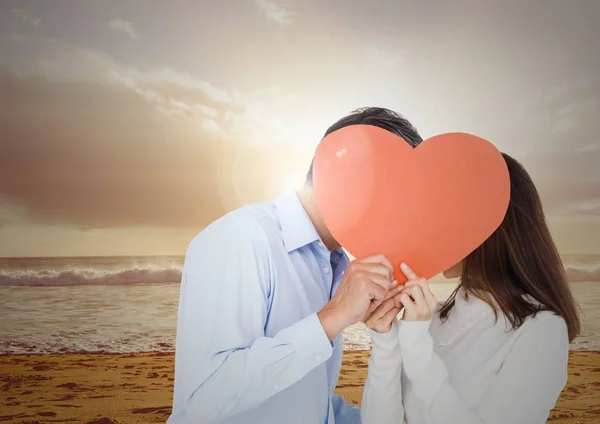 Romantický pár schovává svou tvář za červené srdce — Stock fotografie