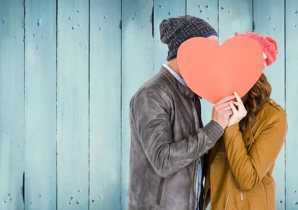 Couple cachant leur visage derrière coeur rouge — Photo