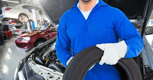 Mechanic holding tyre at garage — Stock Photo, Image