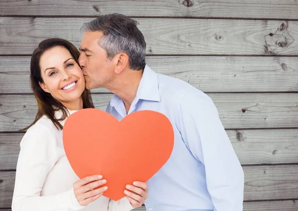 Volwassen man die een vrouw kussen bedrijf rood hart — Stockfoto