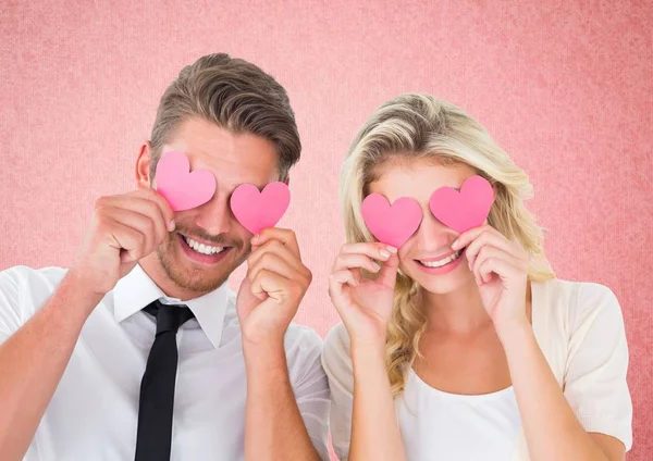 Casal segurando corações sobre os olhos — Fotografia de Stock