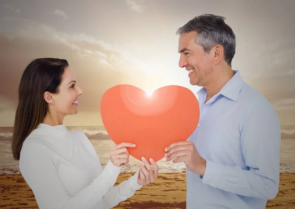 Paar holding rood hart op strand — Stockfoto