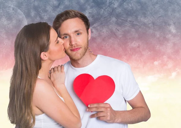 Woman kissing while man holding red heart — Stock Photo, Image