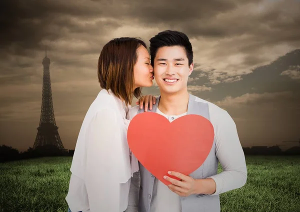 Woman kissing man while holding heart — Stock Photo, Image