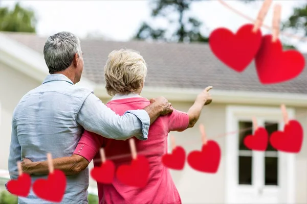 Senior couple pointing towards house — Stock Photo, Image