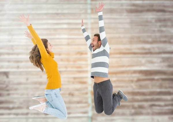 Coppia saltando contro muro mattoni — Foto Stock