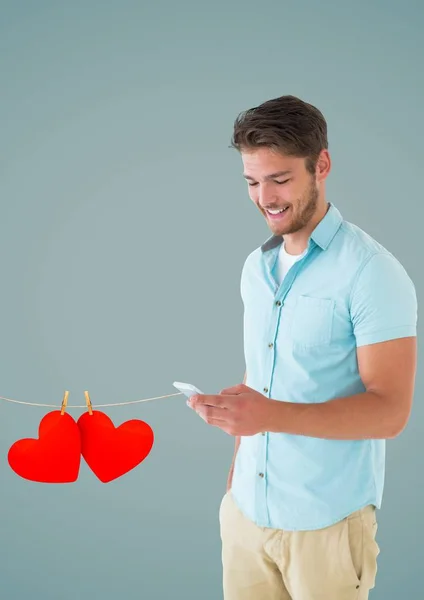 Homme souriant textos et pendaison coeurs rouges — Photo