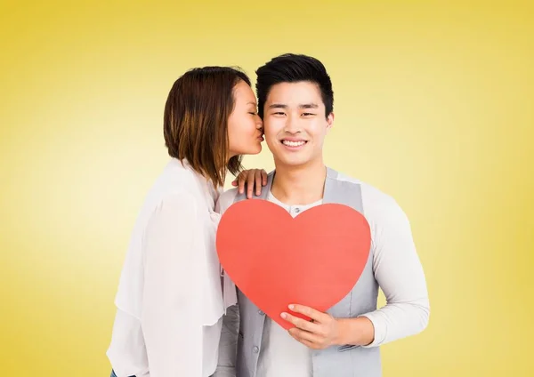 Woman kissing man while holding heart — Stock Photo, Image