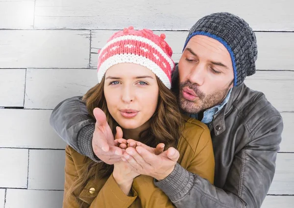 Romantic couple in winter clothing blowing snow — Stock Photo, Image