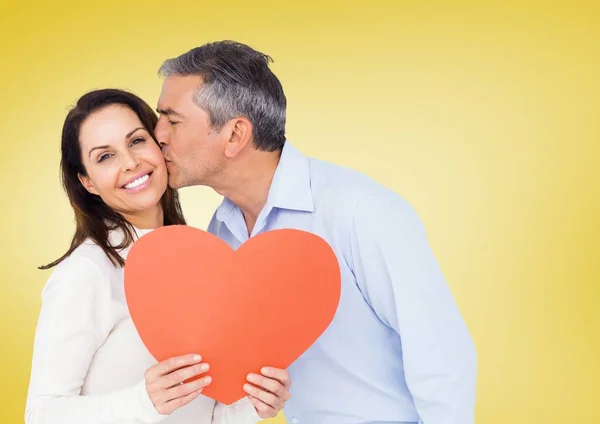 Зрелый мужчина целует женщину с красным сердцем — стоковое фото