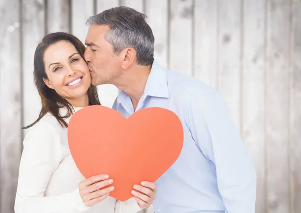 Hombre besando mujer sosteniendo un corazón — Foto de Stock