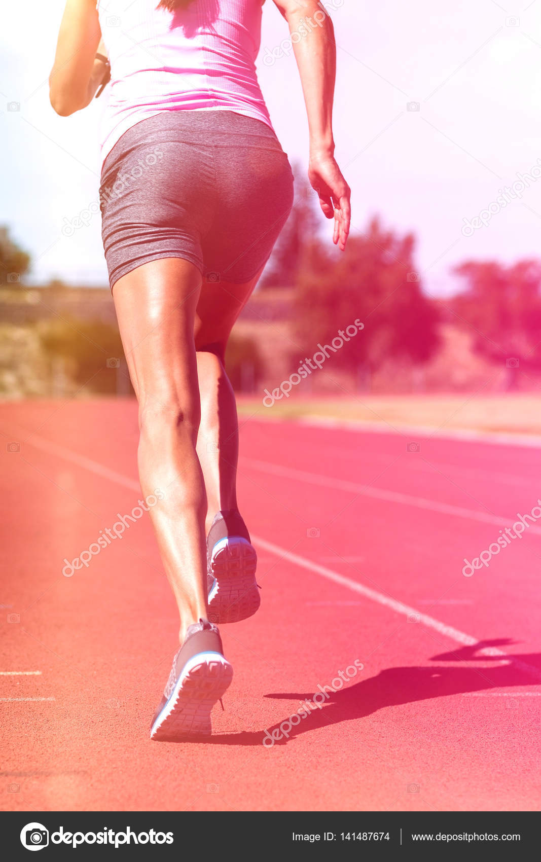 Rear view of female athlete running on running track Stock Photo by