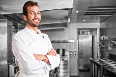 Smiling young chef standing with arms crossed clipart