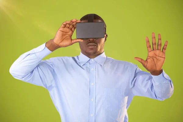 Σύνθετη εικόνα του ανθρώπου με το σετ κεφαλής εικονικής πραγματικότητας σε πράσινο φόντο — Φωτογραφία Αρχείου