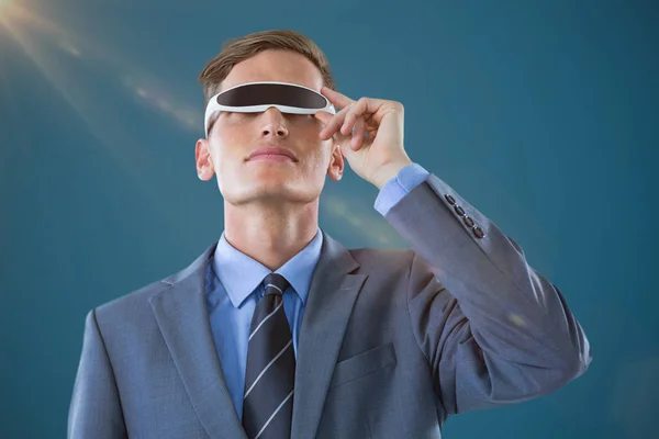 Composietbeeld van zakenman met behulp van virtual reality bril tegen blauwe achtergrond — Stockfoto