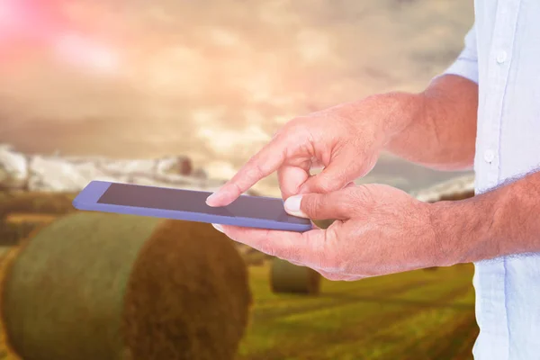 Композиционное изображение человека, использующего планшетный компьютер на фоне полевого пейзажа — стоковое фото