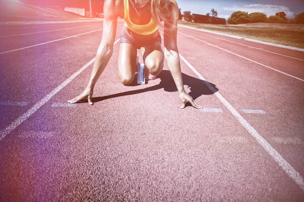 Atleta feminina pronta para correr em pista de corrida — Fotografia de Stock