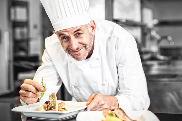 Lächelnder männlicher Koch garniert Essen in der Küche — Stockfoto