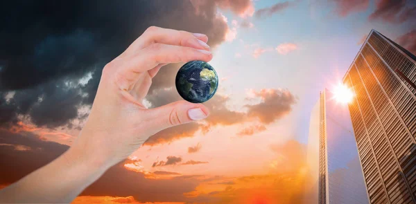Composite image of woman presenting little earth with her hand — Stock Photo, Image