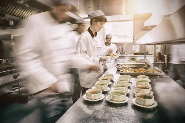 Vier chef-koks werken in een moderne keuken — Stockfoto