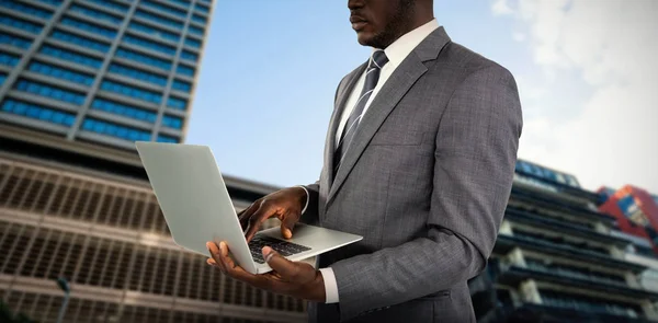 Imagem composta do midsection do homem de negócios usando laptop — Fotografia de Stock