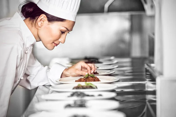 Chef femenino concentrado decorando comida en la cocina — Foto de Stock