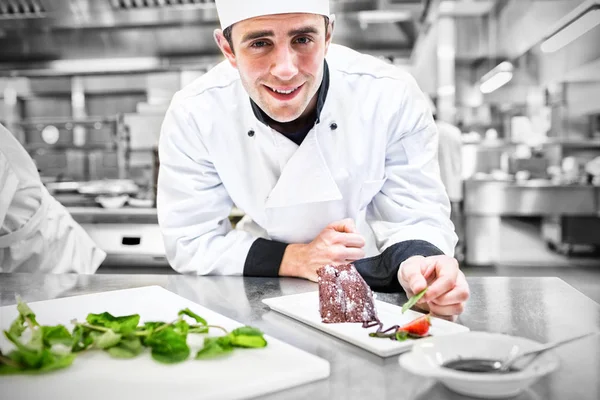 Chef sonriente poniendo menta con su postre — Foto de Stock
