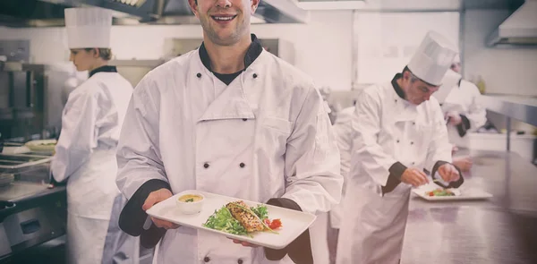 Счастливый шеф-повар держит лососевое блюдо — стоковое фото