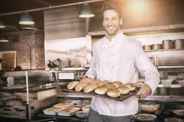 Joyeux boulanger montrant plateau avec du pain — Photo