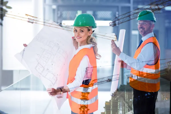 Kollegen halten Pläne auf Baustelle hoch — Stockfoto