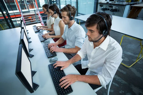 Business executives with headsets using computer — Stock Photo, Image
