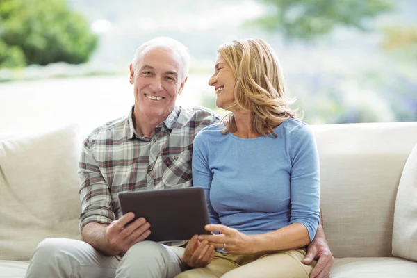 Glimlachend senior paar zittend op de Bank met digitale tablet in woonkamer — Stockfoto