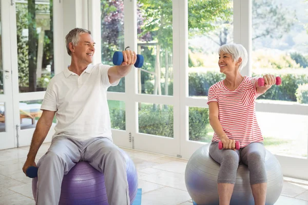 Casal sênior exercitando com haltere na bola de exercício — Fotografia de Stock