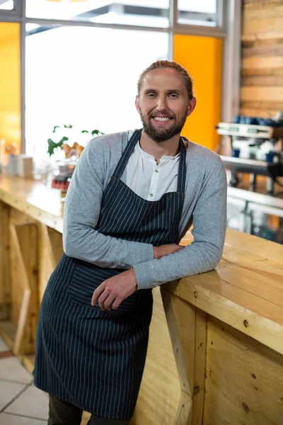 Porträtt av leende servitör lutar på counter — Stockfoto