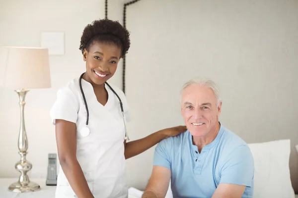 Porträt einer lächelnden Krankenschwester und eines älteren Mannes im Schlafzimmer — Stockfoto