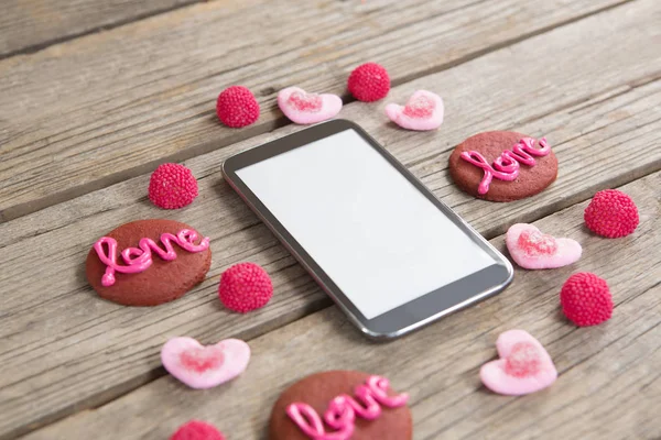 Mobiele telefoon omringd met koekjes en zoetwaren — Stockfoto