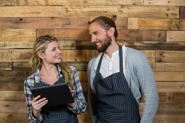 Lächelnder Kellner und Kellnerin mit digitalem Tablet gegen Holzwand — Stockfoto