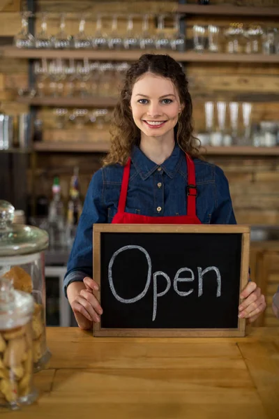 Ler servitris visar tavlan med öppna tecken på counter — Stockfoto
